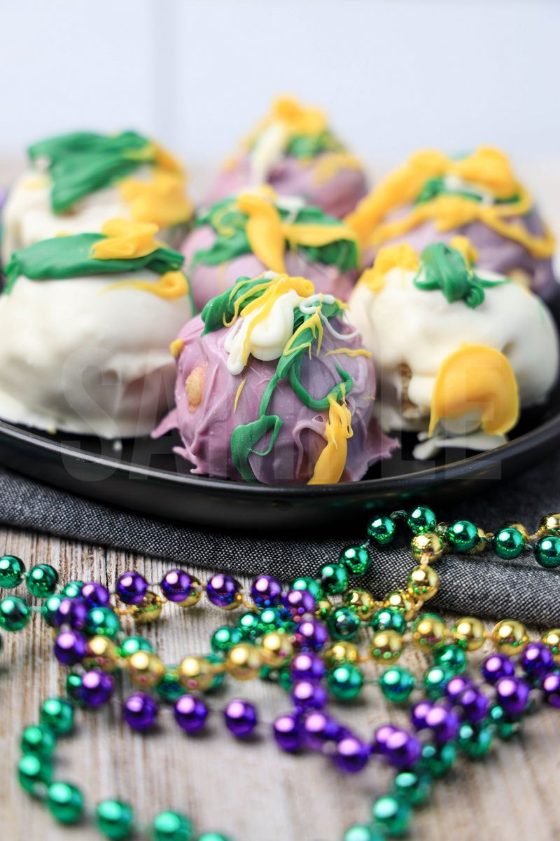 The Mardi Gras Oreo Balls comes on a black plate with a denim napkin on a rustic wood backdrop.
