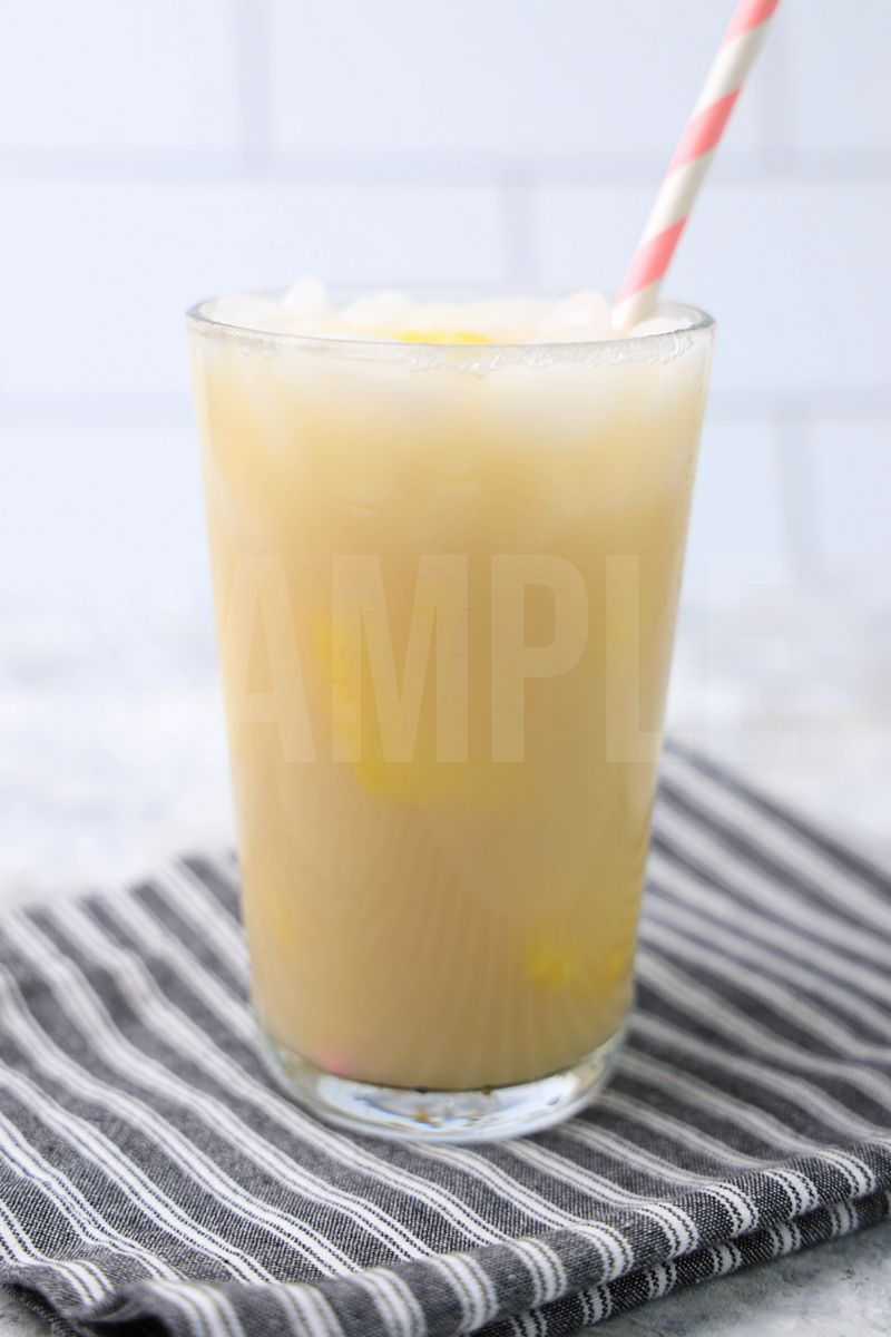 The Paradise Drink comes in a clear glass with a gray striped napkin on a marble backdrop.