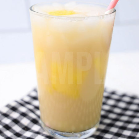 The Paradise Drink comes in a clear glass with a plaid napkin on a white wood backdrop.