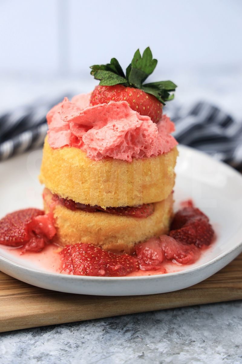 The Strawberry Shortcake comes on a white plate with a gray striped napkin on a marble backdrop.