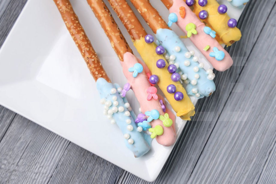 The Easter Pretzel Rods comes on a white plate on a gray wood backdrop.