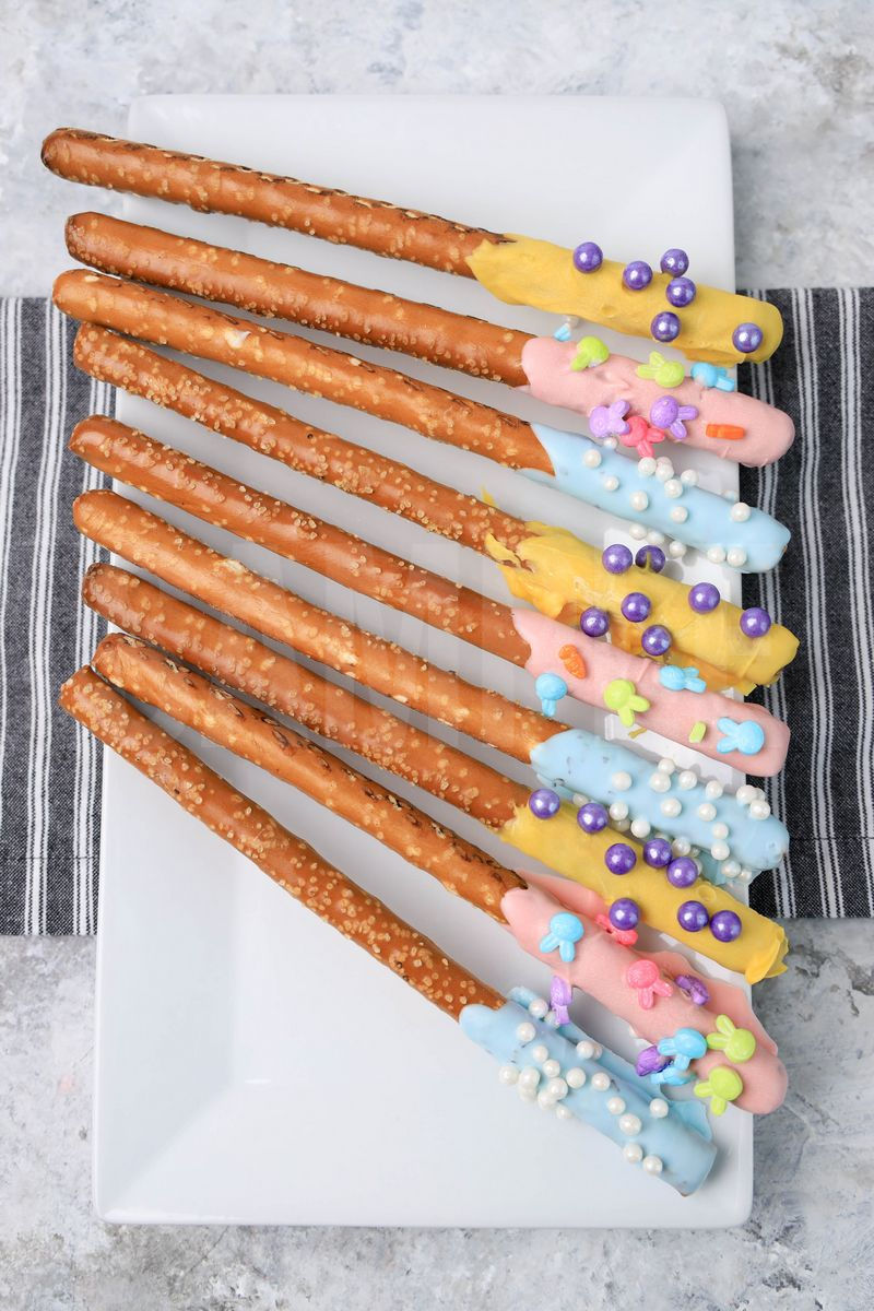 The Easter Pretzel Rods comes on a white plate on a gray striped napkin with a marble backdrop.