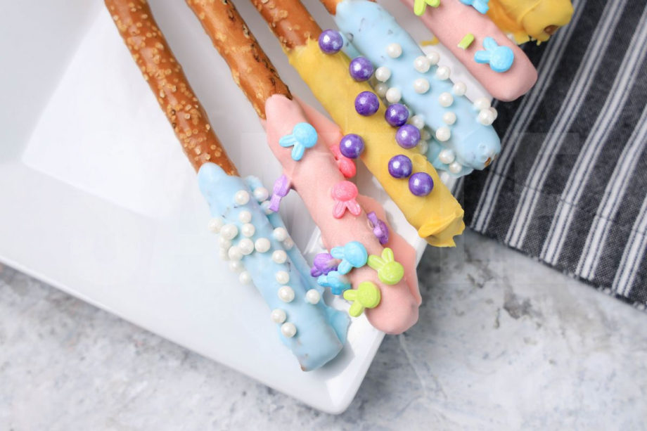 The Easter Pretzel Rods comes on a white plate on a gray striped napkin with a marble backdrop.