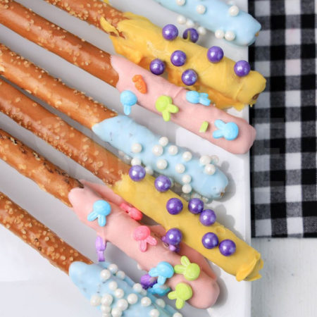 The Easter Pretzel Rods comes on a white plate on a plaid napkin with a white wood backdrop.