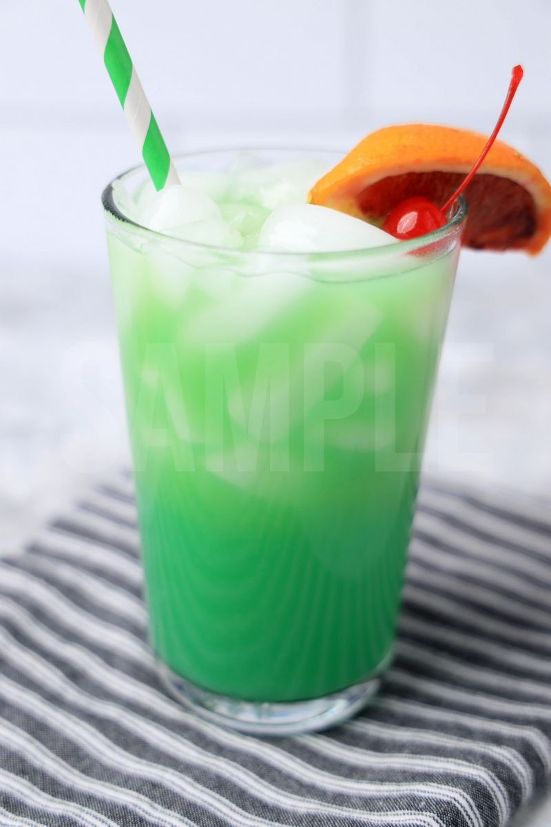 The Green Drunken Leprechaun comes in a clear glass with a gray striped napkin on a marble backdrop.