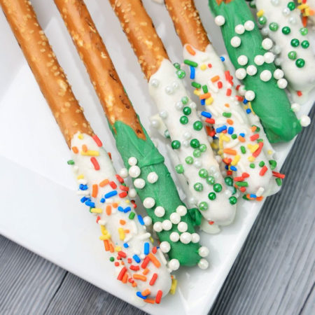 The St. Patrick's Pretzel Rods comes on a white plate on a white striped napkin with a gray wood backdrop.