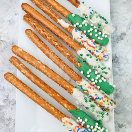 The St. Patrick's Pretzel Rods comes on a white plate on a gray striped napkin with a marble backdrop.