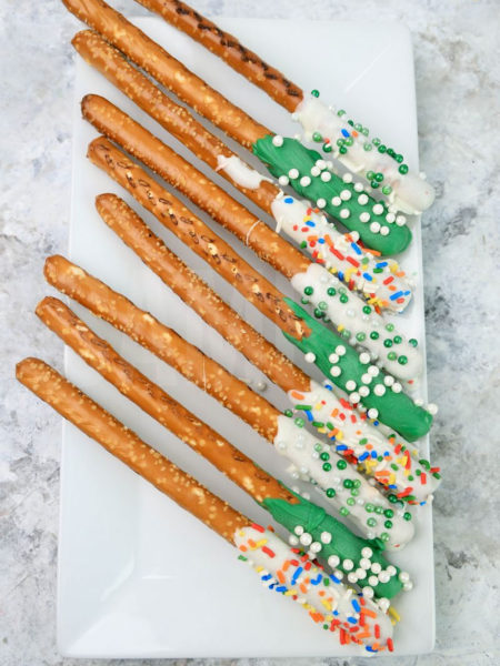 The St. Patrick's Pretzel Rods comes on a white plate on a gray striped napkin with a marble backdrop.