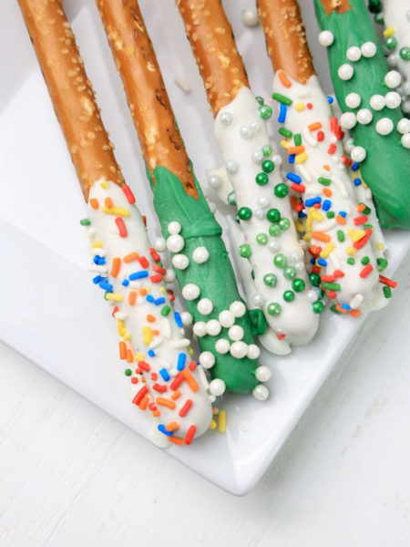 The St. Patrick's Pretzel Rods comes on a white plate on a plaid napkin with a white wood backdrop.
