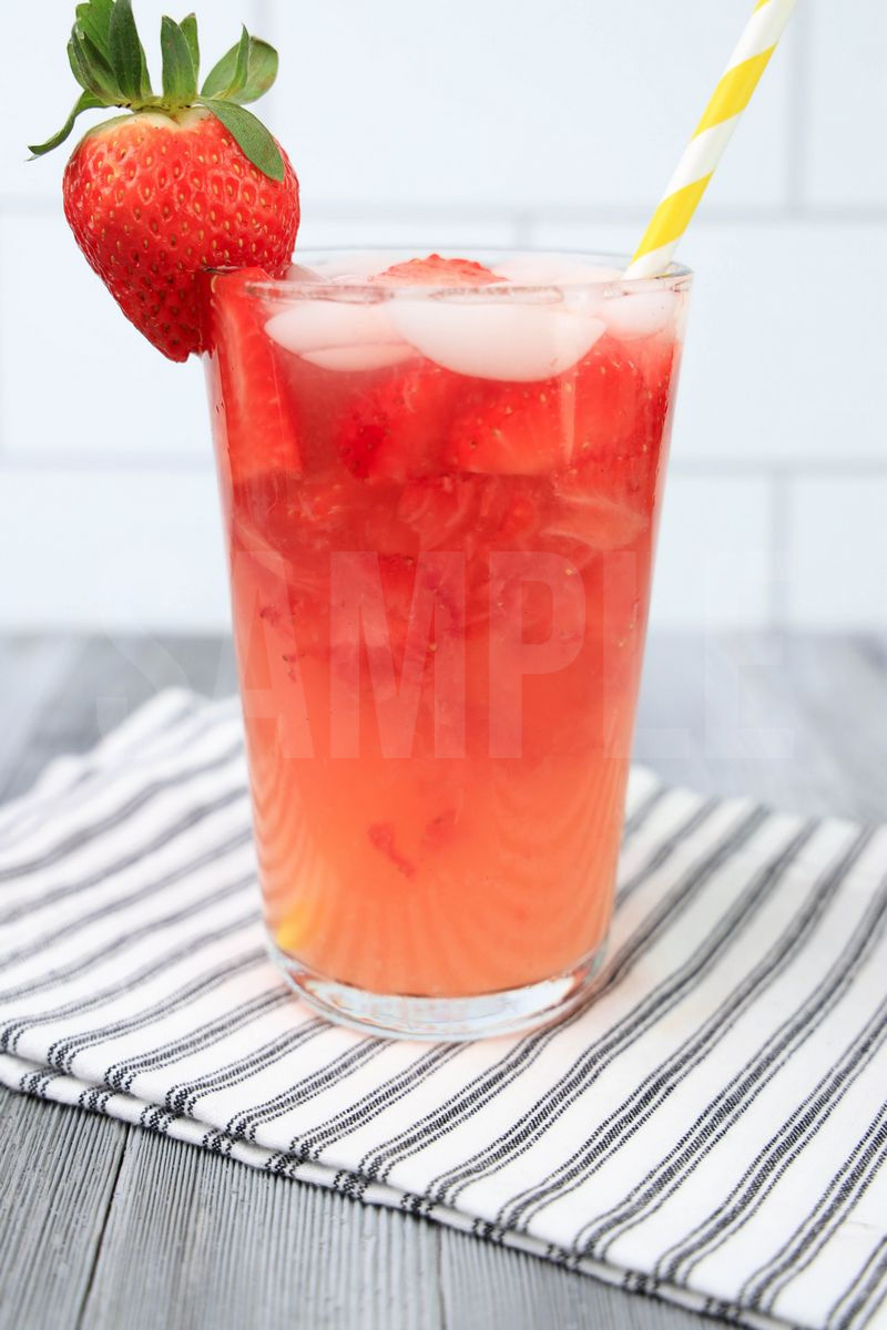 The Starbuck's Strawberry Acai Lemonade Copycat comes in a clear glass with a white striped napkin on a gray wood backdrop.