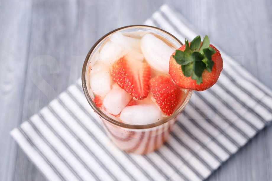 The Starbuck's Strawberry Acai Refresher Copycat comes in a clear glass with a white striped napkin on a gray wood backdrop.