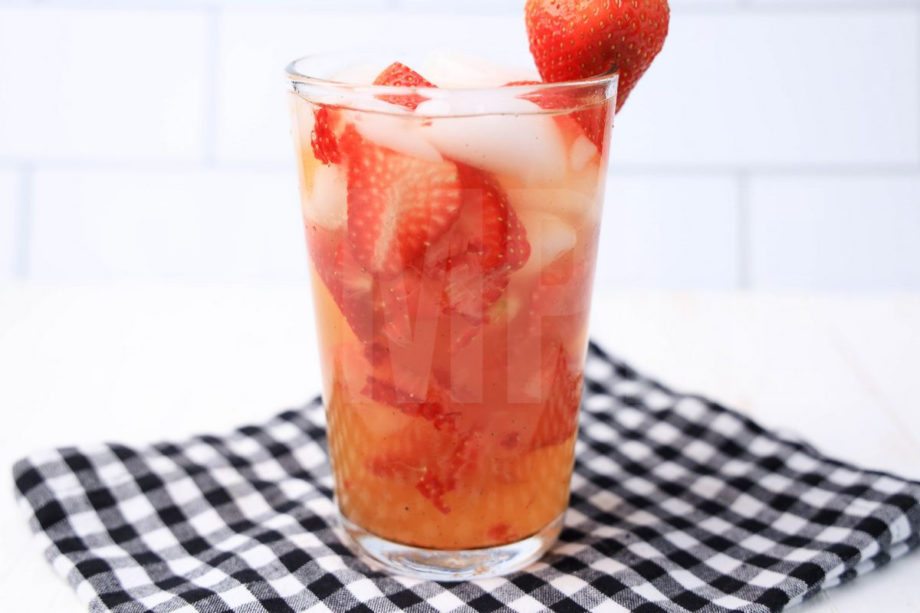 The Starbuck's Strawberry Acai Refresher Copycat comes in a clear glass with a plaid napkin on a white wood backdrop.