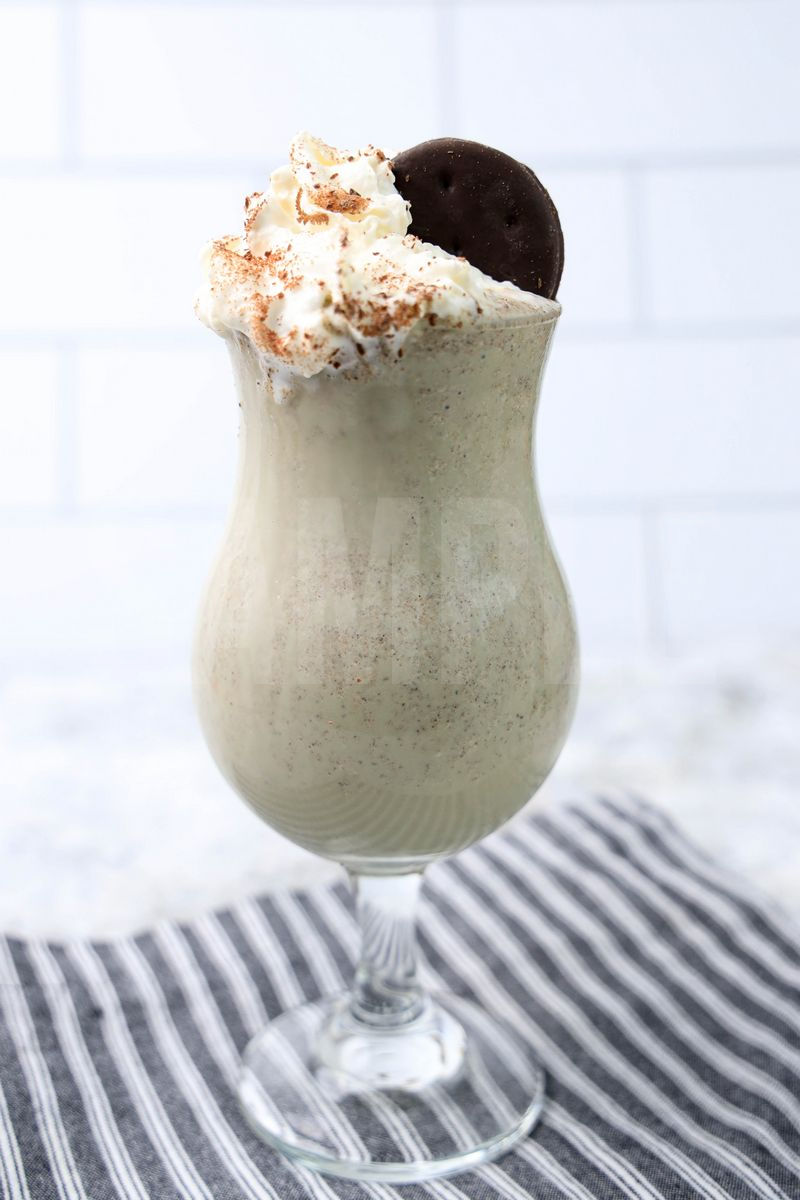 hin Mint Shake comes in a clear glass with a gray striped napkin on a marble backdrop.