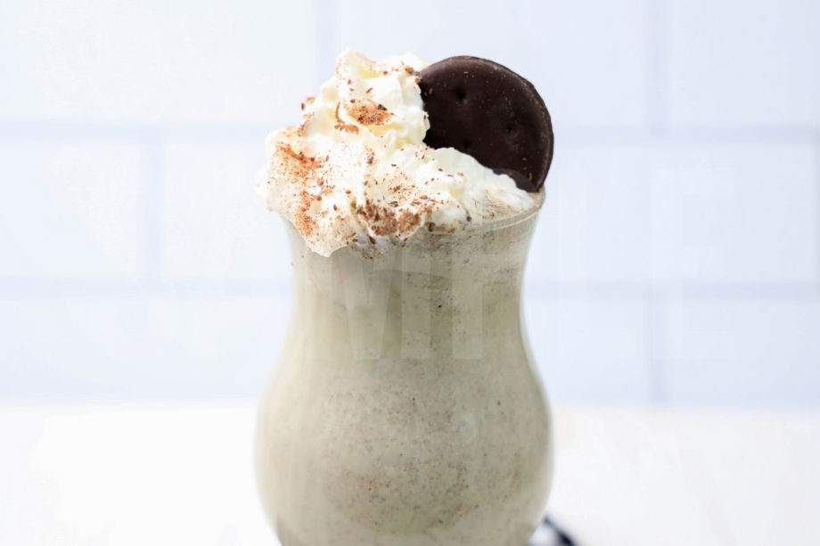 Thin Mint Shake comes in a clear glass with a plaid napkin on a white wood backdrop.