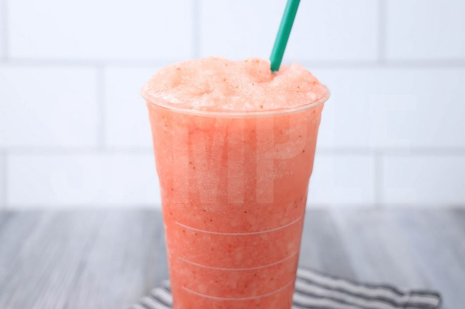 The Blended Strawberry Lemonade comes in a venti cup with a gray striped napkin on a gray wood backdrop.