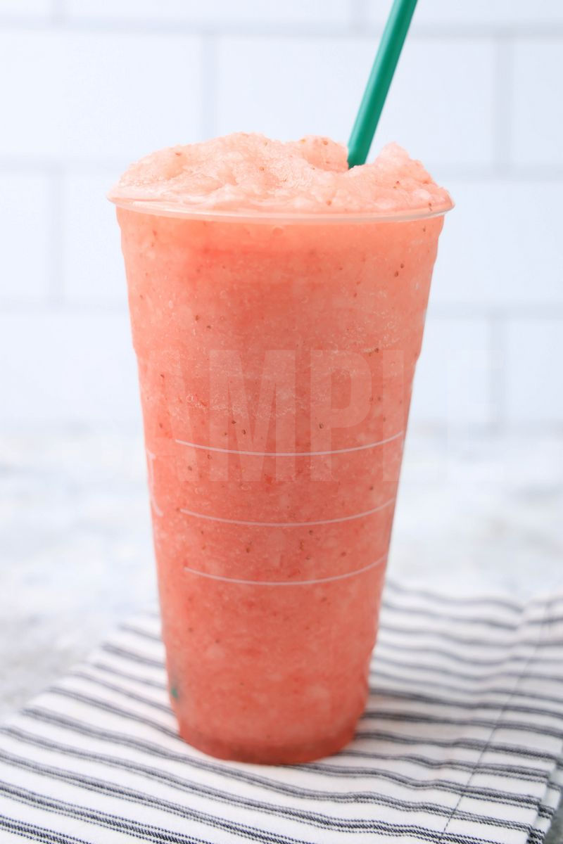 The Blended Strawberry Lemonade comes in a venti cup with a white striped napkin on a marble backdrop.