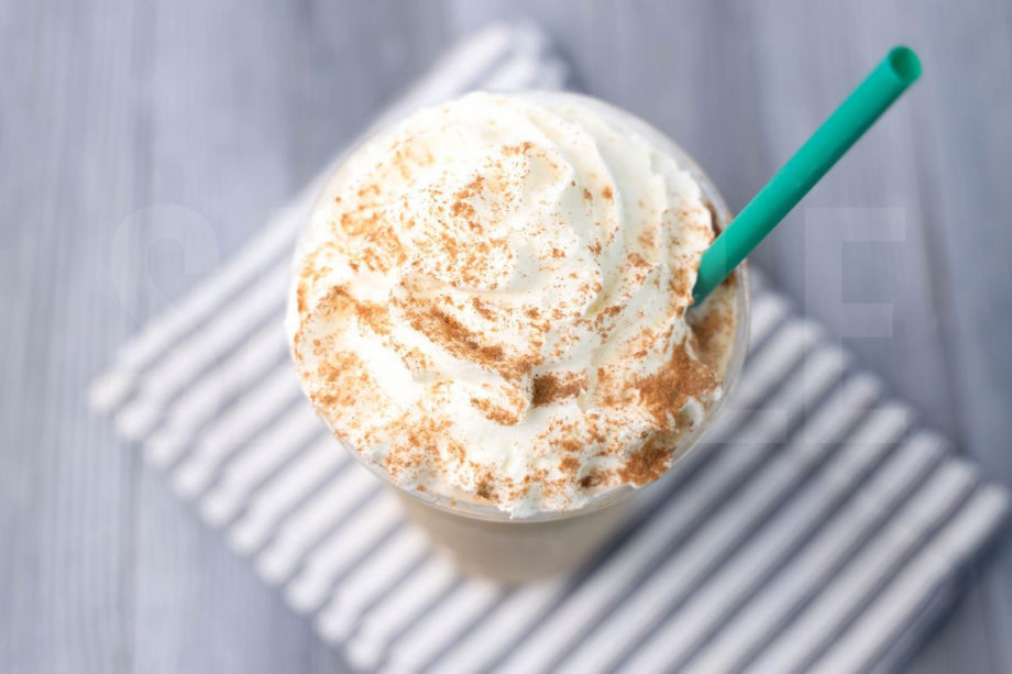 The Chai Crème Frappuccino comes in a venti cup with a white striped napkin on a gray wood backdrop.