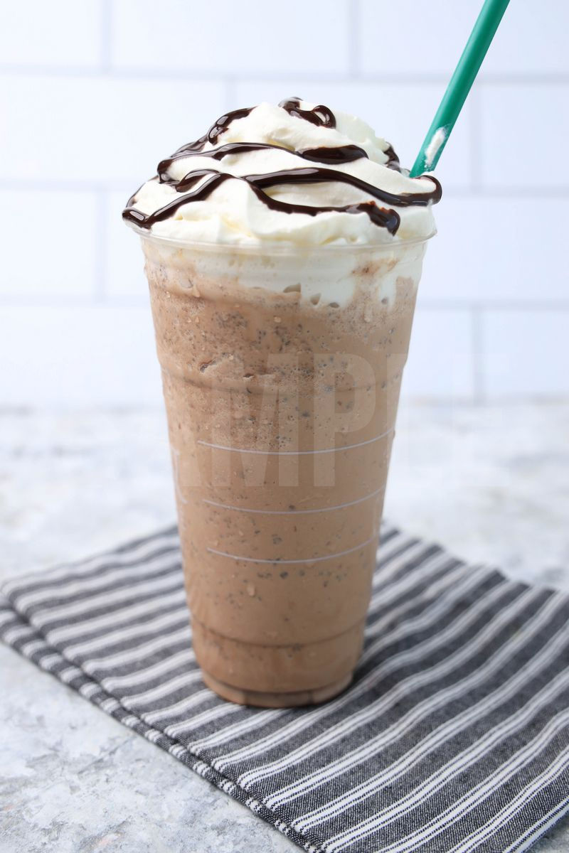 The Double Chocolaty Chip Crème Frappuccino comes in a venti cup with a gray striped napkin on a marble backdrop.