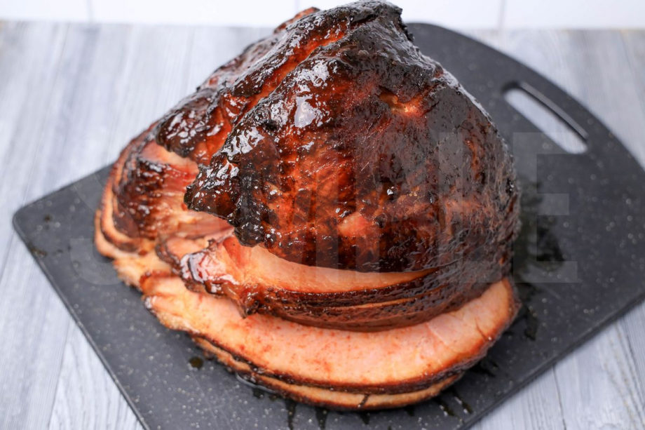 The Double Smoked Ham comes on a black speckled cutting board on a gray wood backdrop.