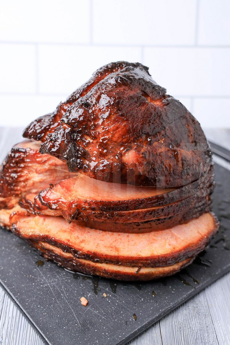 The Double Smoked Ham comes on a black speckled cutting board on a gray wood backdrop.