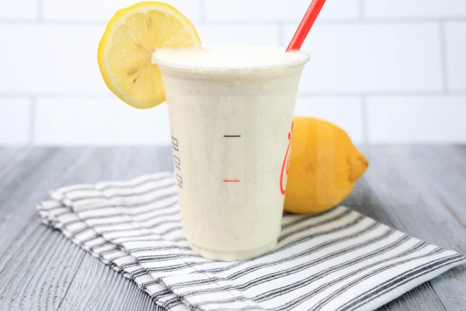 The Frosted Lemonade Chick Fil A Copycat comes in a cup with a white striped napkin on a gray wood backdrop.
