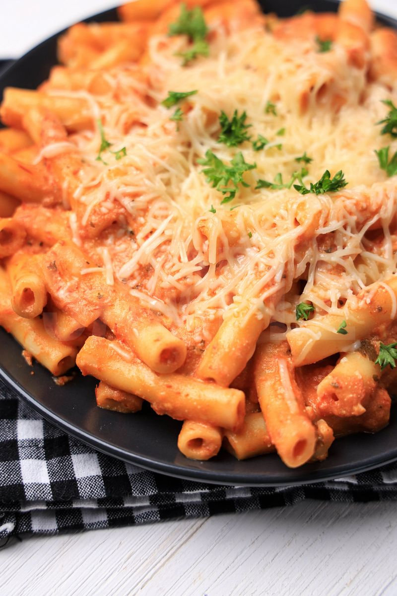 The Five Cheese Ziti Al Forno Olive Garden Copycat comes on a gray plate with a plaid napkin on a white wood backdrop.