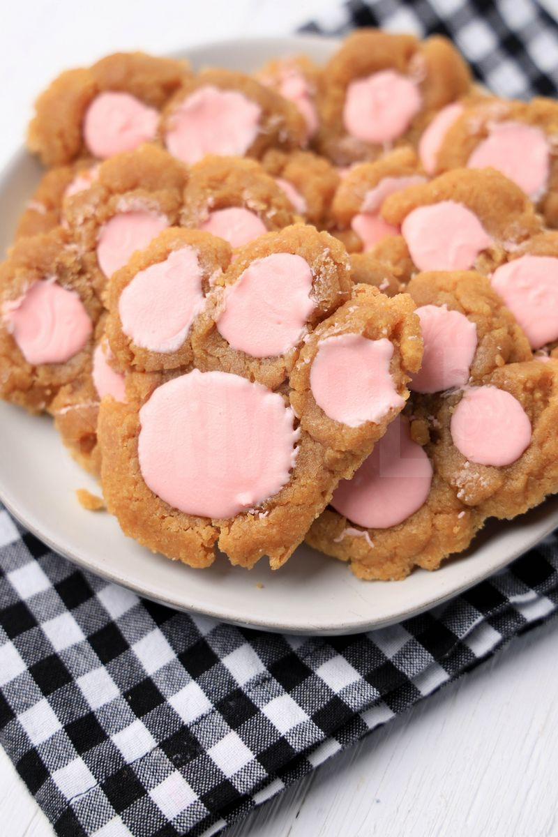 The Peanut Butter Bunny Paw Cookies comes on a white plate with a plaid napkin on a white wood backdrop.