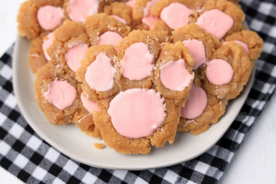 The Peanut Butter Bunny Paw Cookies comes on a white plate with a plaid napkin on a white wood backdrop.