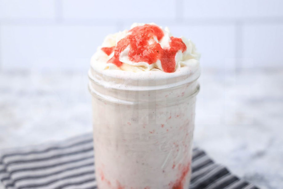 The Strawberry Crème Frappuccino comes in a jar with a gray striped napkin on a marble backdrop.