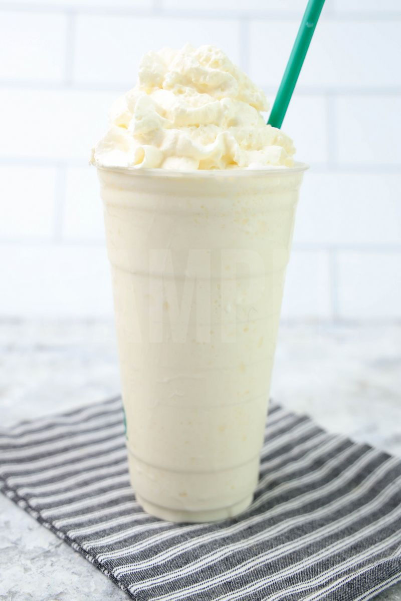 The White Chocolate Crème Frappuccino comes in a venti cup with a gray striped napkin on a marble backdrop.