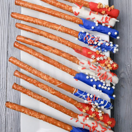 The 4th Of July Pretzel Rods comes on a white plate with a gray wood backdrop.