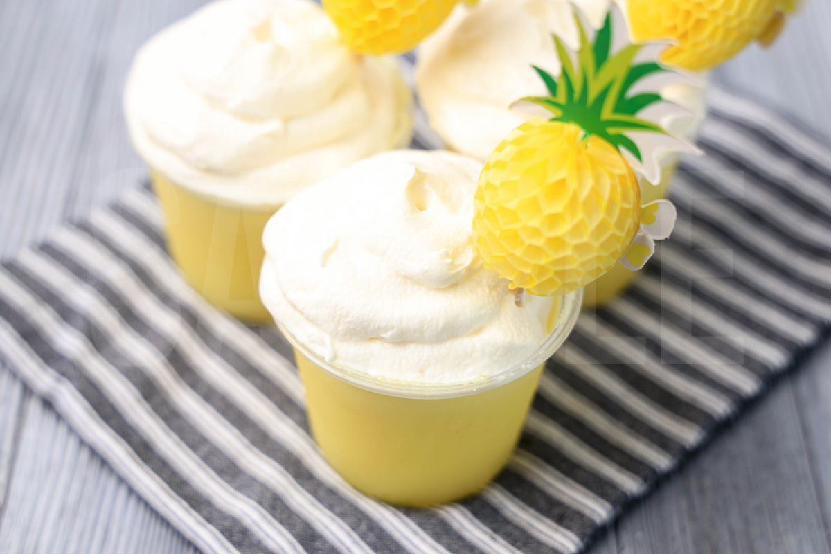 The Dole Whip Jello Shots comes on gray striped napkin on a gray wood backdrop.
