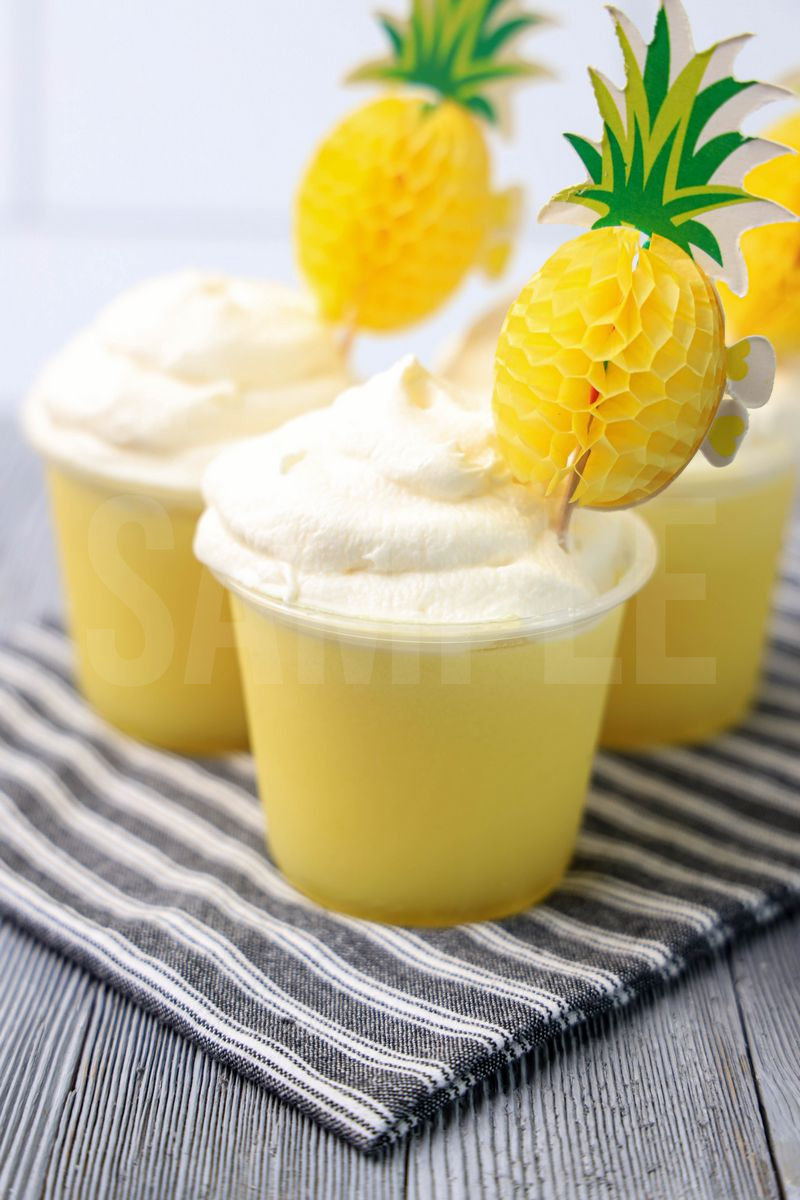 The Dole Whip Jello Shots comes on gray striped napkin on a gray wood backdrop.
