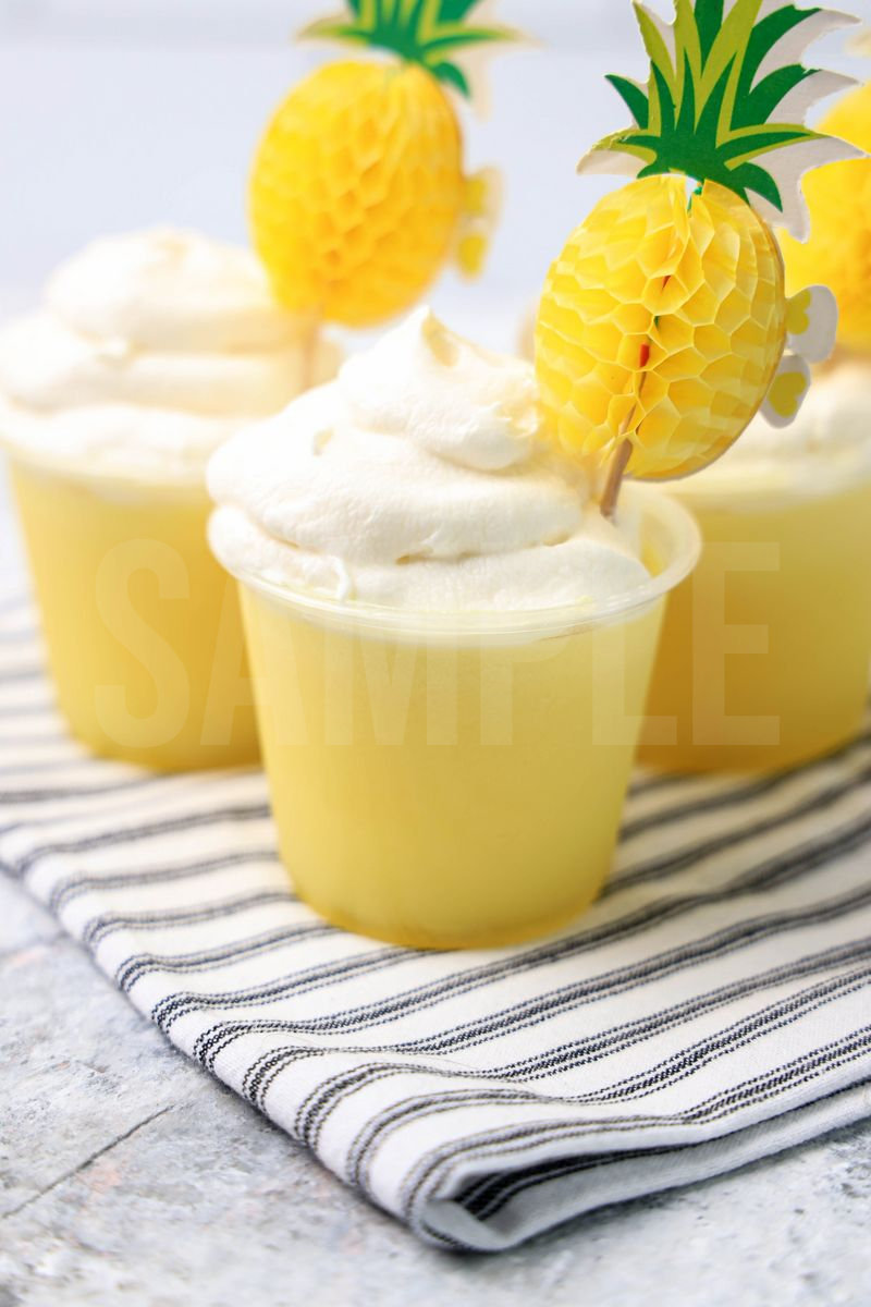 The Dole Whip Jello Shots comes on white striped napkin on a marble backdrop.