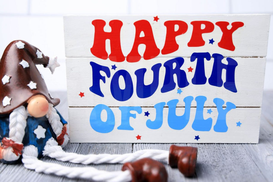 The Happy Fourth Of July Farmhouse Wood Cricut Craft comes pictured on a gray wood backdrop.