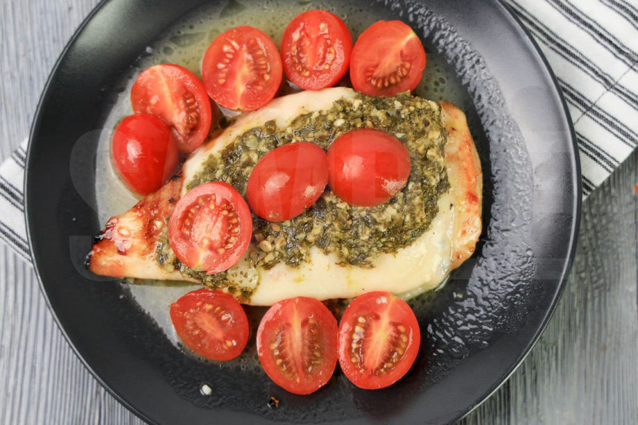 The Olive Garden Copycat Grilled Chicken Margherita comes on a white striped napkin on a gray plate with a gray wood backdrop.