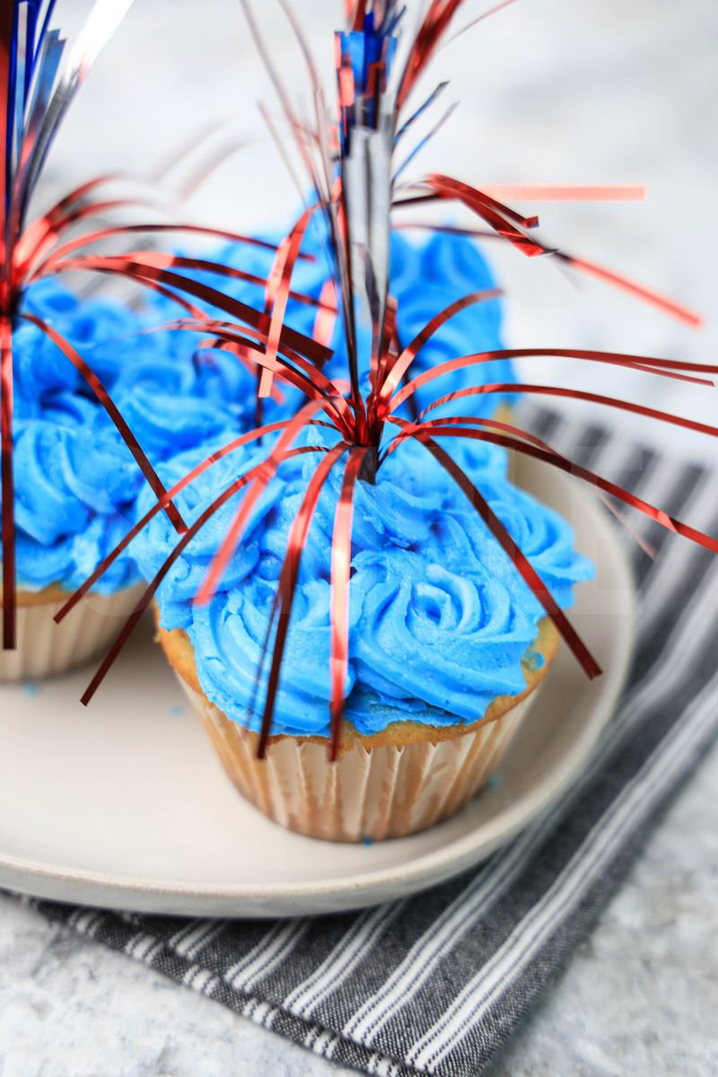 The 4th Of July Sparkler Cupcakes comes on a gray striped napkin on a marble backdrop.