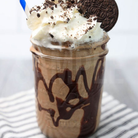 The Double Chocolate Oreo Milkshake comes in a glass jar on a white striped napkin on a gray wood backdrop.