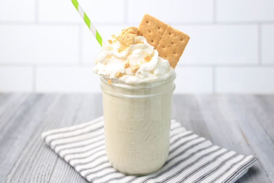 The Key Lime Pie Milkshake comes in a glass jar on a white striped napkin on a gray wood backdrop.