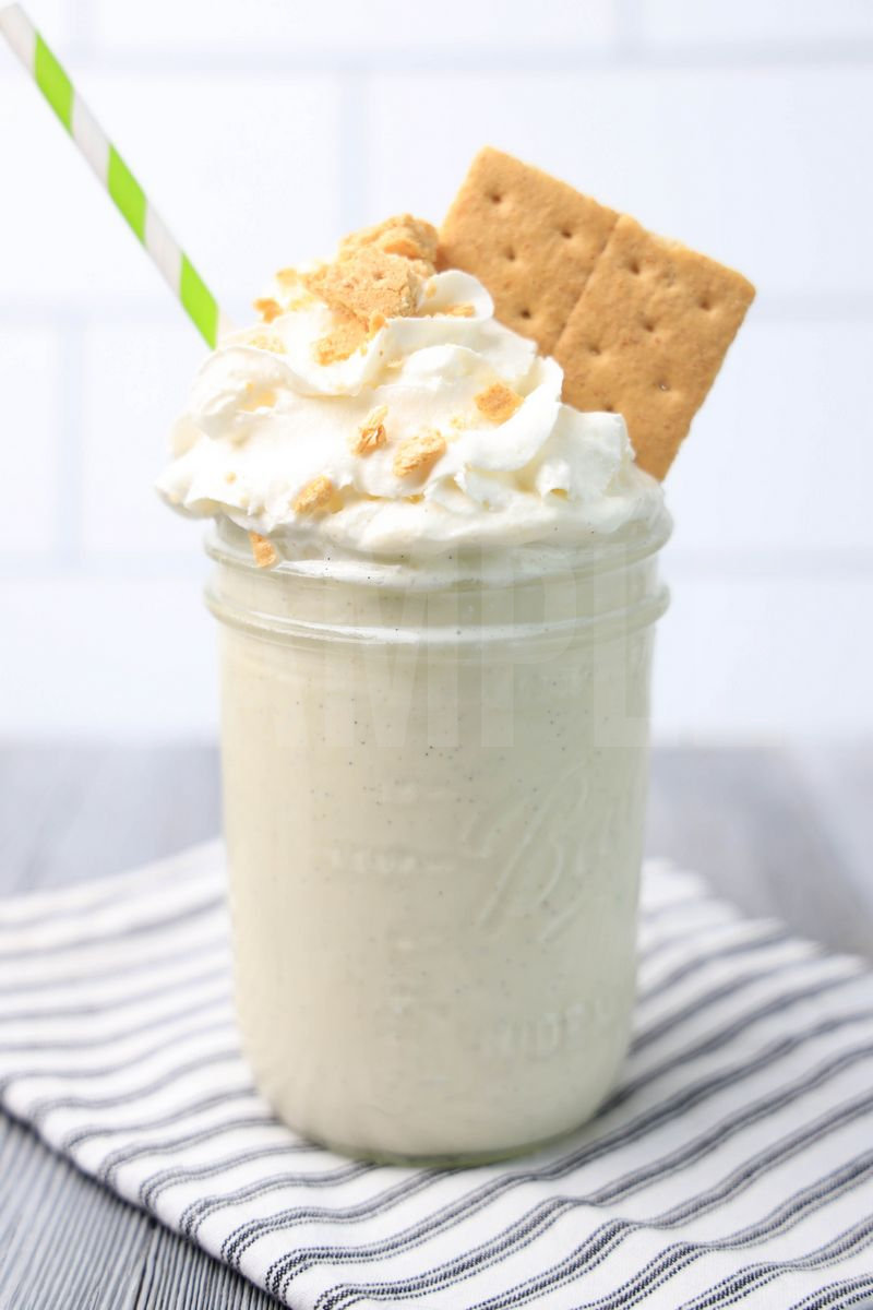 The Key Lime Pie Milkshake comes in a glass jar on a white striped napkin on a gray wood backdrop.