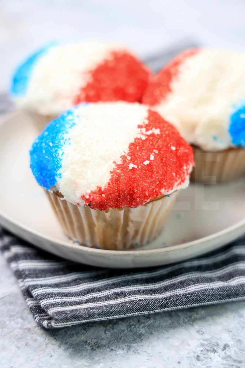 The Snow Cone Cupcakes comes on a gray striped napkin on a marble backdrop.