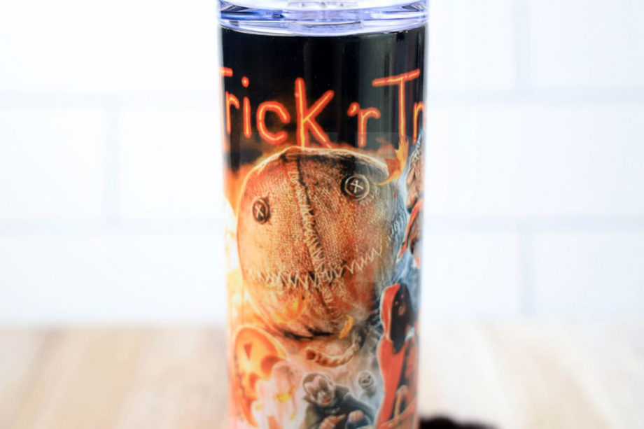 The Trick 'R Treat Sublimation Tumbler Exclusive comes on a rustic wood backdrop.