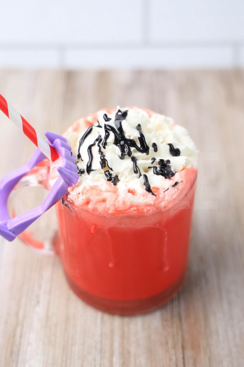 The Vampire Hot Chocolate comes in a glass coffee mug on a rustic wood backdrop.