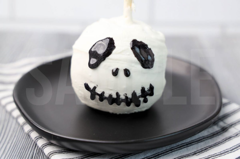 The Jack Skellington Candy Apples comes on a black plate with a white striped napkin on a gray wood backdrop.
