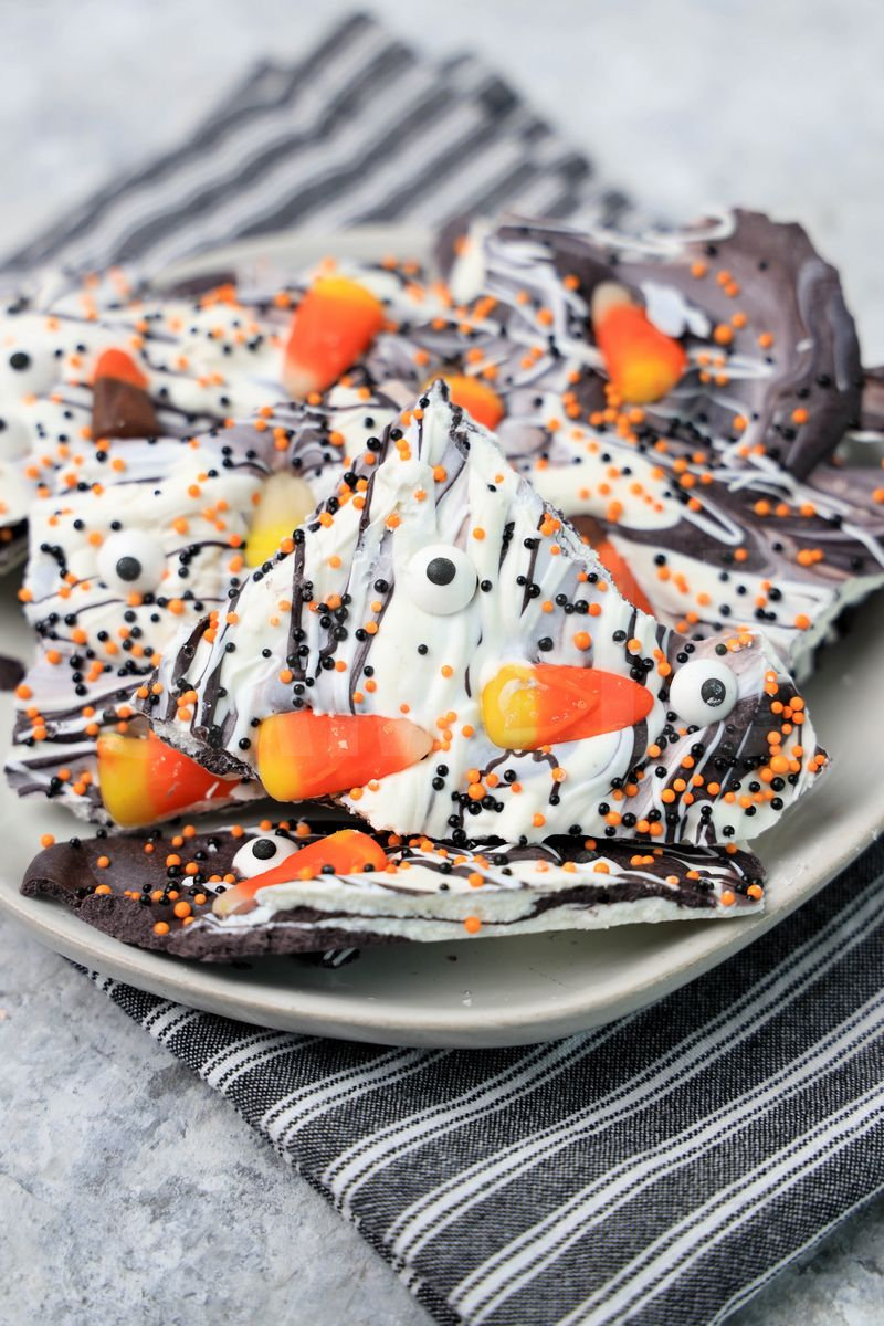 The Vintage Halloween Candy Bark comes on a white plate with a gray striped napkin on a marble backdrop.