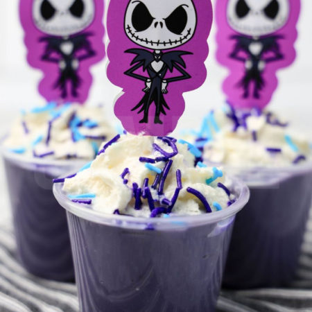The Jack Skellington Pudding Shots comes on a gray striped napkin on a marble backdrop.