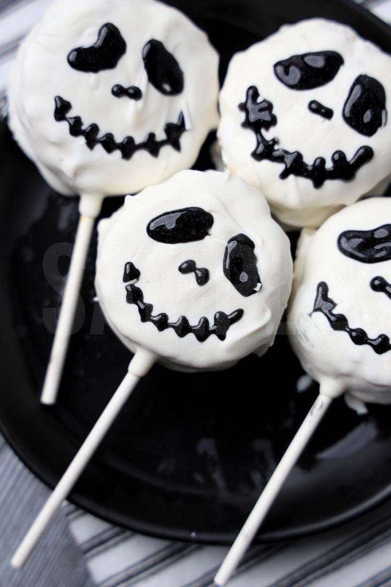 The Nightmare Before Christmas Rice Krispy Pops comes a black plate with a white striped napkin on a gray wood backdrop.