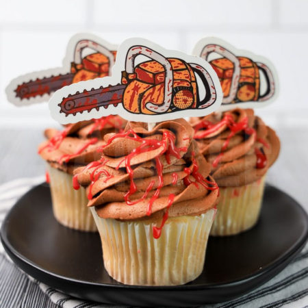 The Texas Chainsaw Cupcakes comes on a black plate on a white striped napkin on a gray wood backdrop.