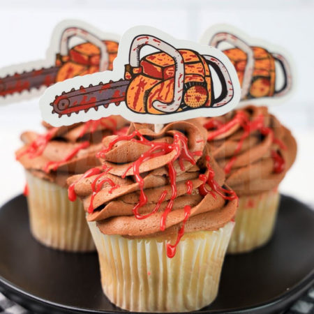 The Texas Chainsaw Cupcakes comes on a black plate on a plaid napkin on a white wood backdrop.