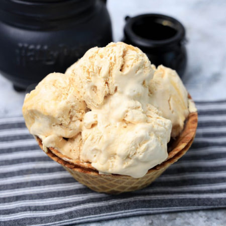The Harry Potter Butterbeer Ice Cream comes in a waffle bowl with a gray striped napkin on a marble backdrop.